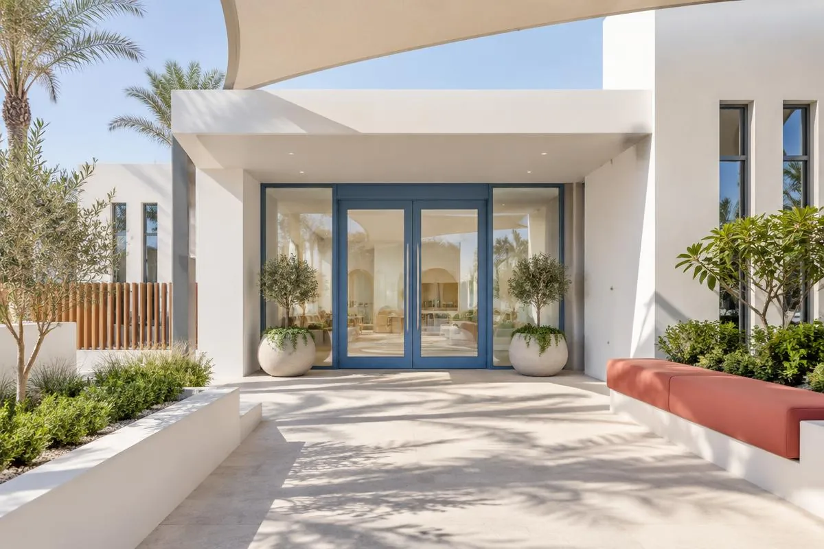 Illustrative image: welcoming nursery entrance with a white facade, blue-framed glass doors and potted plants